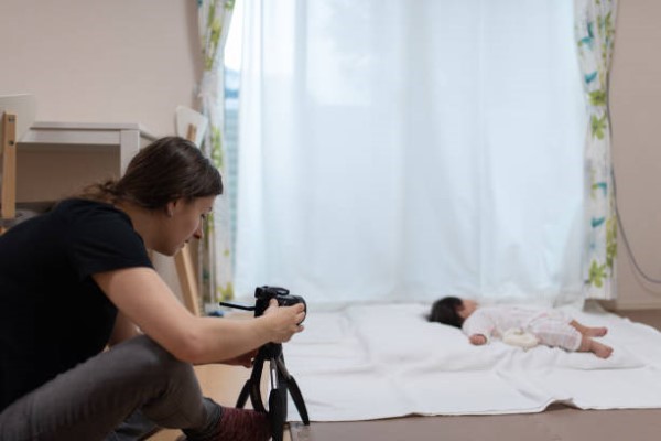 Sesión de fotos para bebés; mujer realizando la sesión de fotos para un bebé con ayuda de un ciclorama