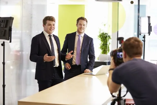 Dos miembros del equipo directivo de una empresa utilizando los videos corporativos como recurso para alcanzar a empleados.