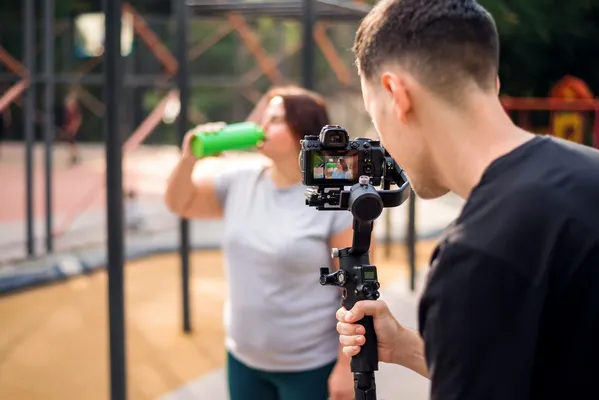 Producción de video en exteriores para el marketing de un producto, dos jóvenes graban contenido en un parque siguiendo las tendencias en producción de video para 2025: lo que tu marca necesita saber.