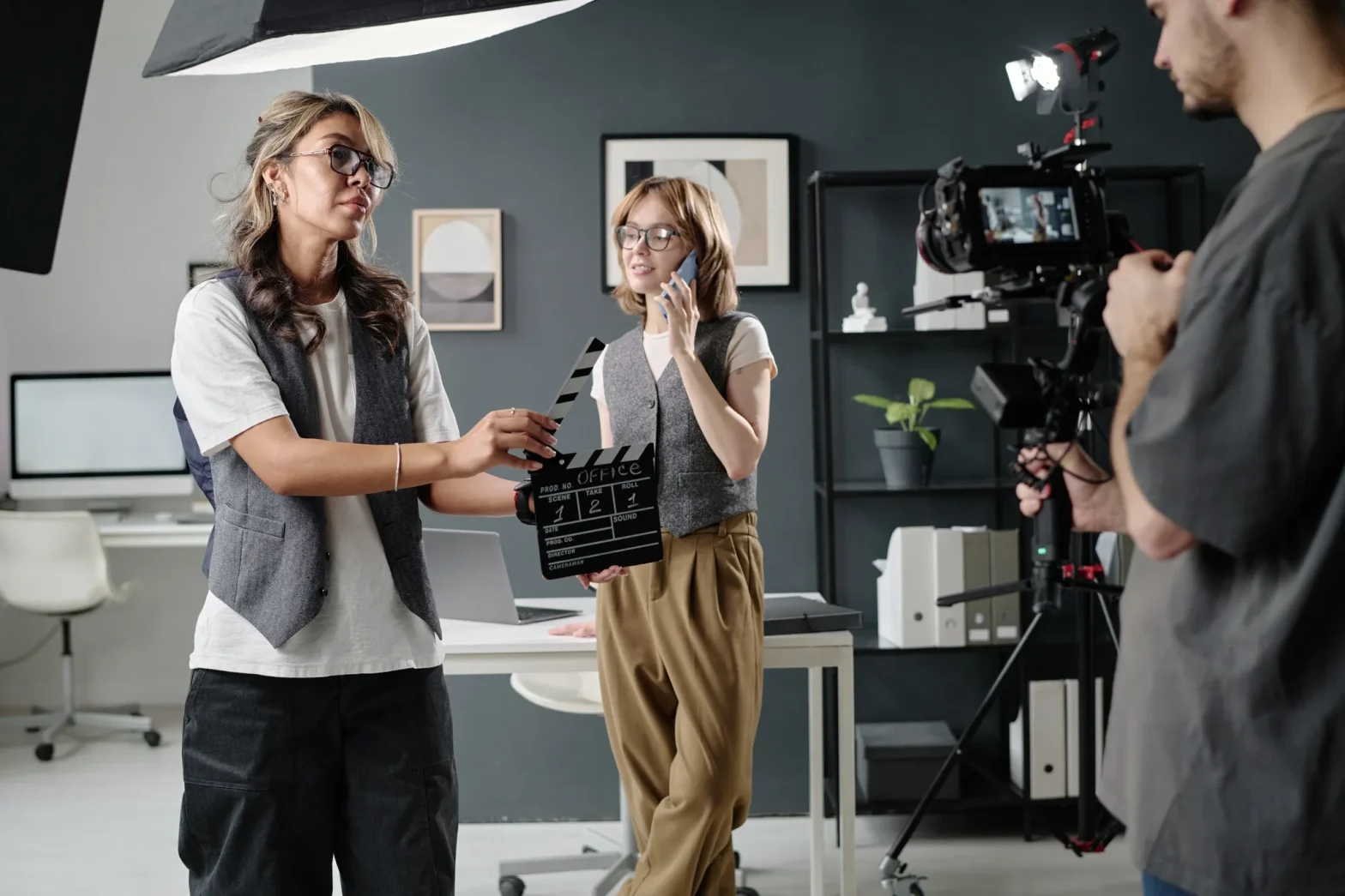 Fotografía de una mujer con claqueta indicando el inicio de la producción de comerciales en un escenario de oficina.