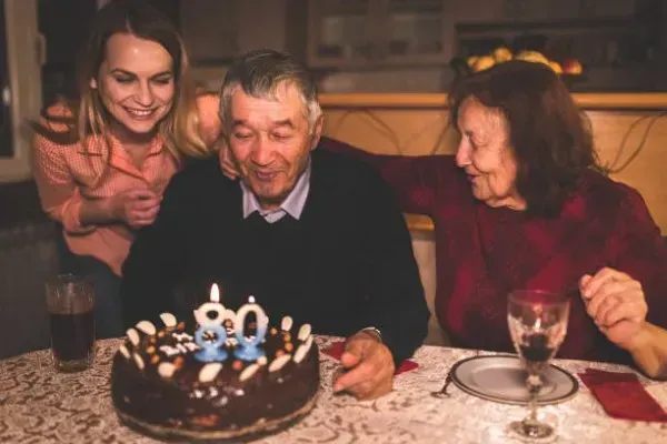 Fotografía de un hombre junto su familia soplando velas de pastel en sus sesión de fotos de cumpleaños