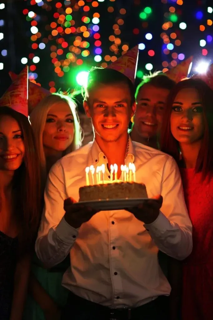 Fotografía de un joven con pastel sonriendo a la cámara para sus sesión de fotos de cumpleaños