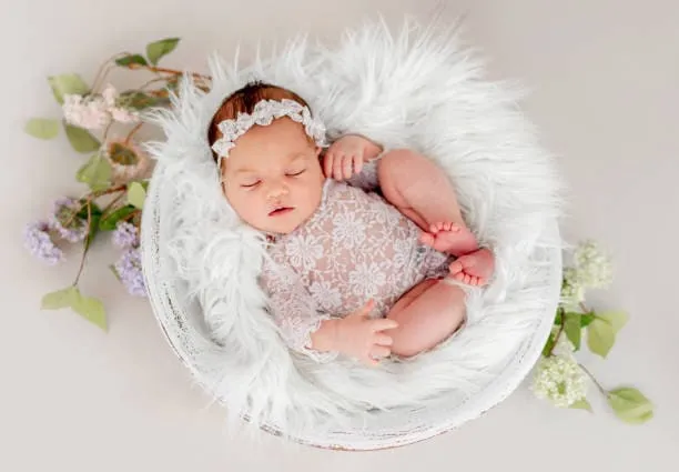 Fotografía de una recién nacida acostada en pequeña cama para una sesión de fotos para bebés