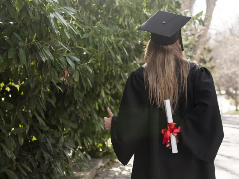 Foto de una universitaria de espaldas sosteniendo su diploma para su sesión de foto de graduación con ARLEX