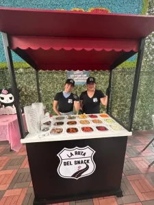 Fotografía de dos chicas de la ruta del snack brindando servicio de la barra de snacks de ARLEX
