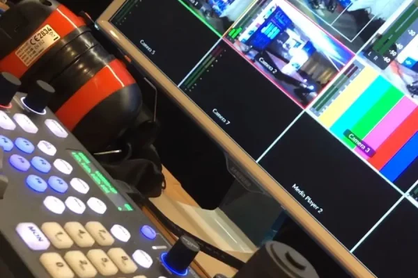 Primer plano de un control de producción con joystick y botones iluminados, utilizado para operar cámaras en un servicio de streaming en vivo.